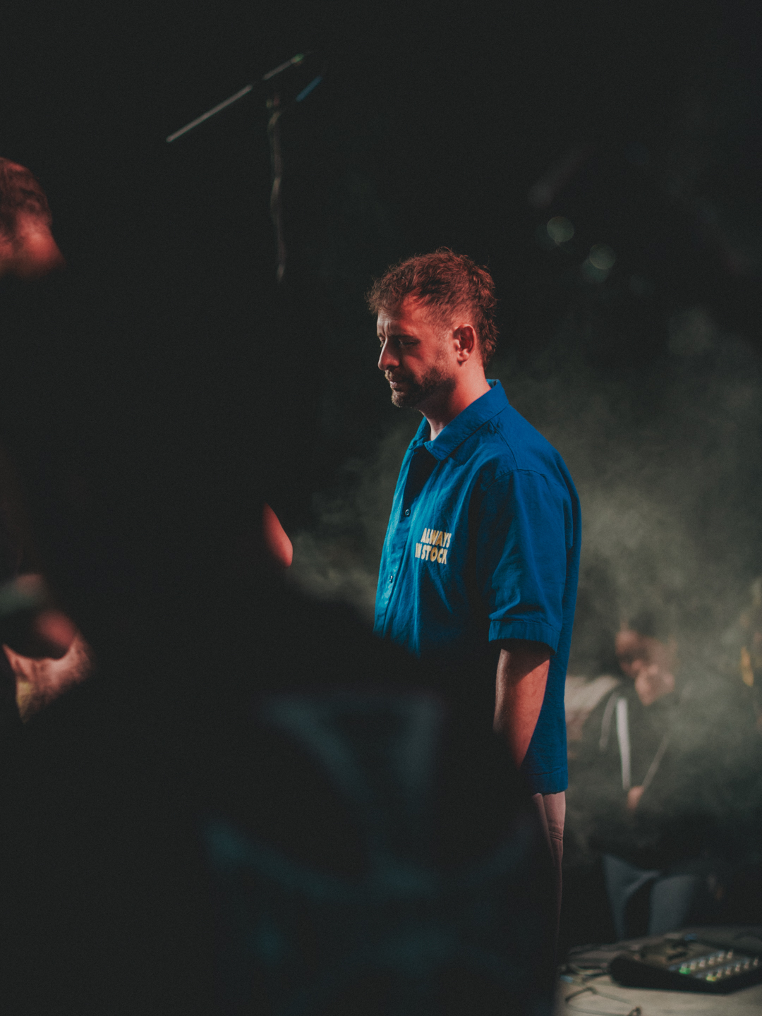 A leader standing in worship under stage light at camp